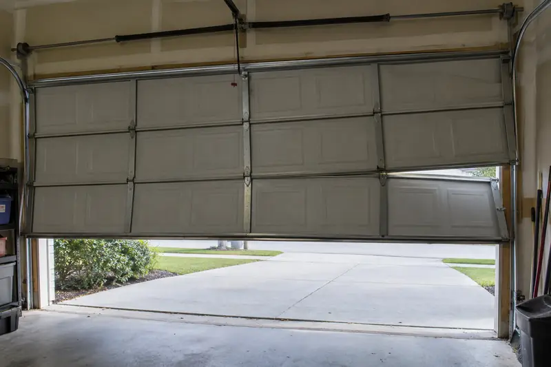 Garage door hanging crooked in its tracks seen from inside the garage